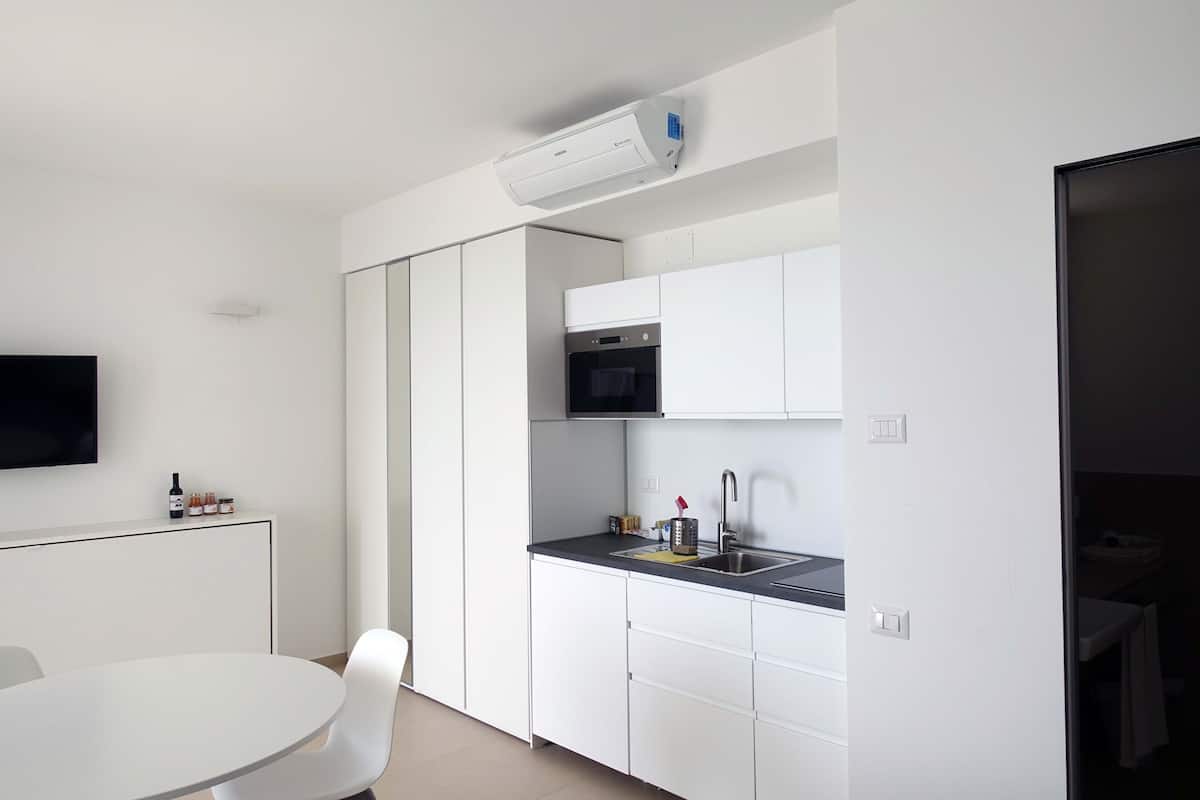 A modern kitchen with white cabinets, a black countertop, and a built-in microwave.