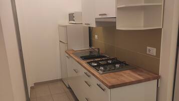 Eine kleine Küche mit einem Gasherd, einer Mikrowelle und einem Kühlschrank.