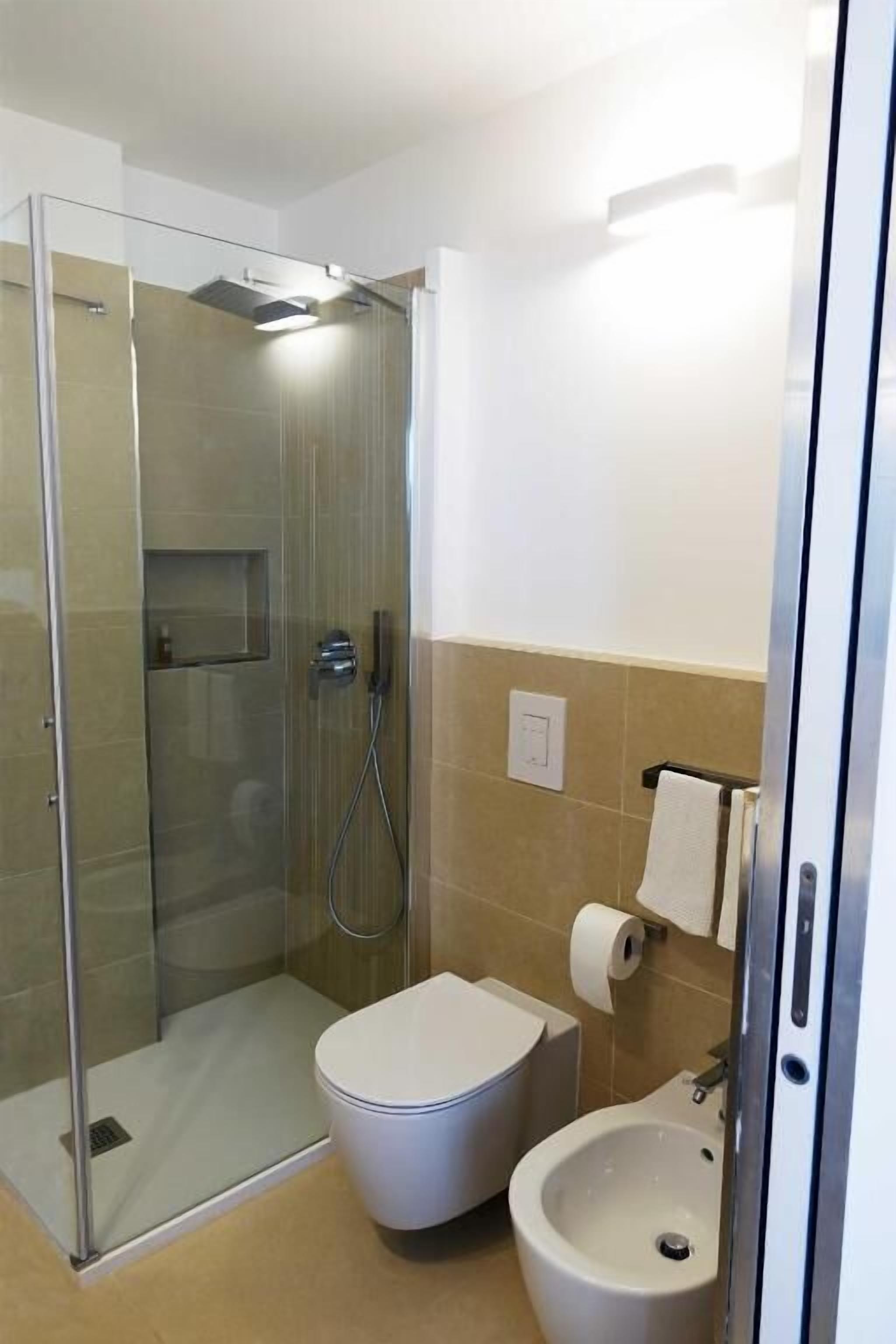 Un baño moderno con ducha de vidrio, inodoro y lavamanos.