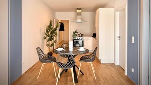 Een modern appartement met een eethoek, keuken en een deur naar een andere kamer.