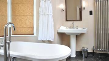 Ein Badezimmer mit freistehender Badewanne, Waschtisch, Spiegel und einem Handtuchhalter mit zwei Handtüchern.
