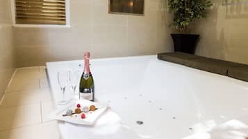 Une salle de bain avec une baignoire, une bouteille de champagne et une assiette de collations.