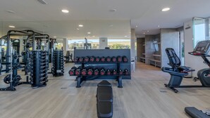 Un gimnasio con equipo de levantamiento de pesas, cintas de correr y una banca.