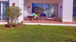 Una casa moderna con un patio que tiene un sofá, sillas y una mesita.