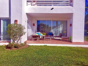 A modern house with a patio area featuring a sofa, chairs, and a small table. - 5-guest Apartment Near Alcazaba Lagoon (Casares)