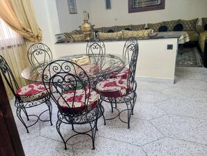 A dining area with a round table and chairs, a sofa, and a decorative stove.