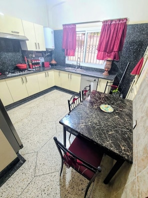 A kitchen with a dining table and chairs, a stove, and a sink.