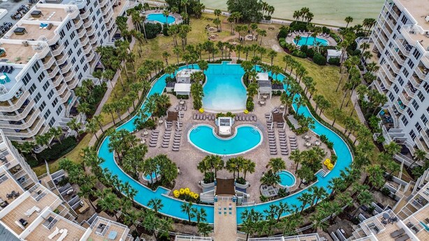 Ein Resort mit mehreren Schwimmpools, Palmen und einem zentralen Pool mit Liegeinsel.