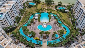 A resort with multiple swimming pools, palm trees, and a central pool with a sunken area. - 2400 Sq Ft | Sleeps 12 | 700ft Lazy River Retreat (Fort Walton Beach)