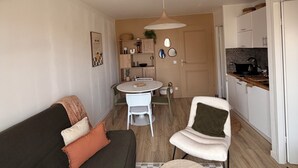 Un ambiente compatto con divano, tavolo da pranzo e angolo cottura.