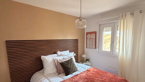 Una camera da letto con un letto grande, una testiera in legno, un comodino con una lampada e una finestra con tende.