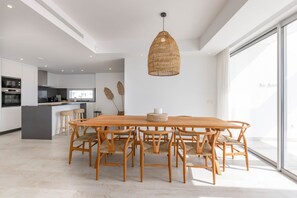 Eine moderne Küche mit weißen Schränken, einer zentralen Kochinsel und einem Essbereich mit Holztisch und Stühlen.