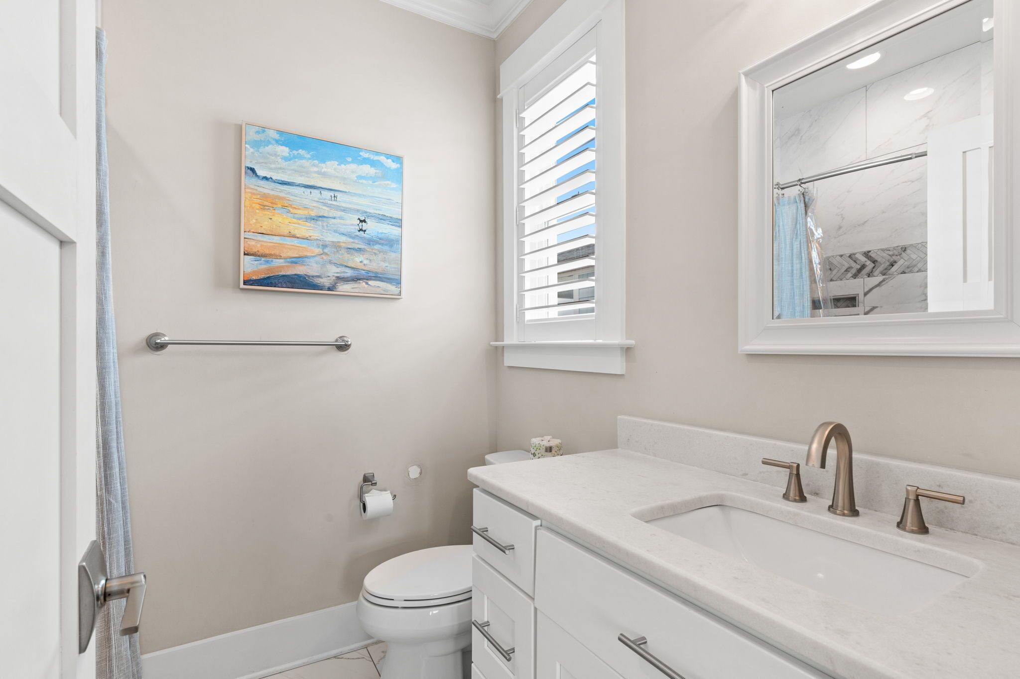 A bathroom with a toilet, sink, and a painting on the wall.
