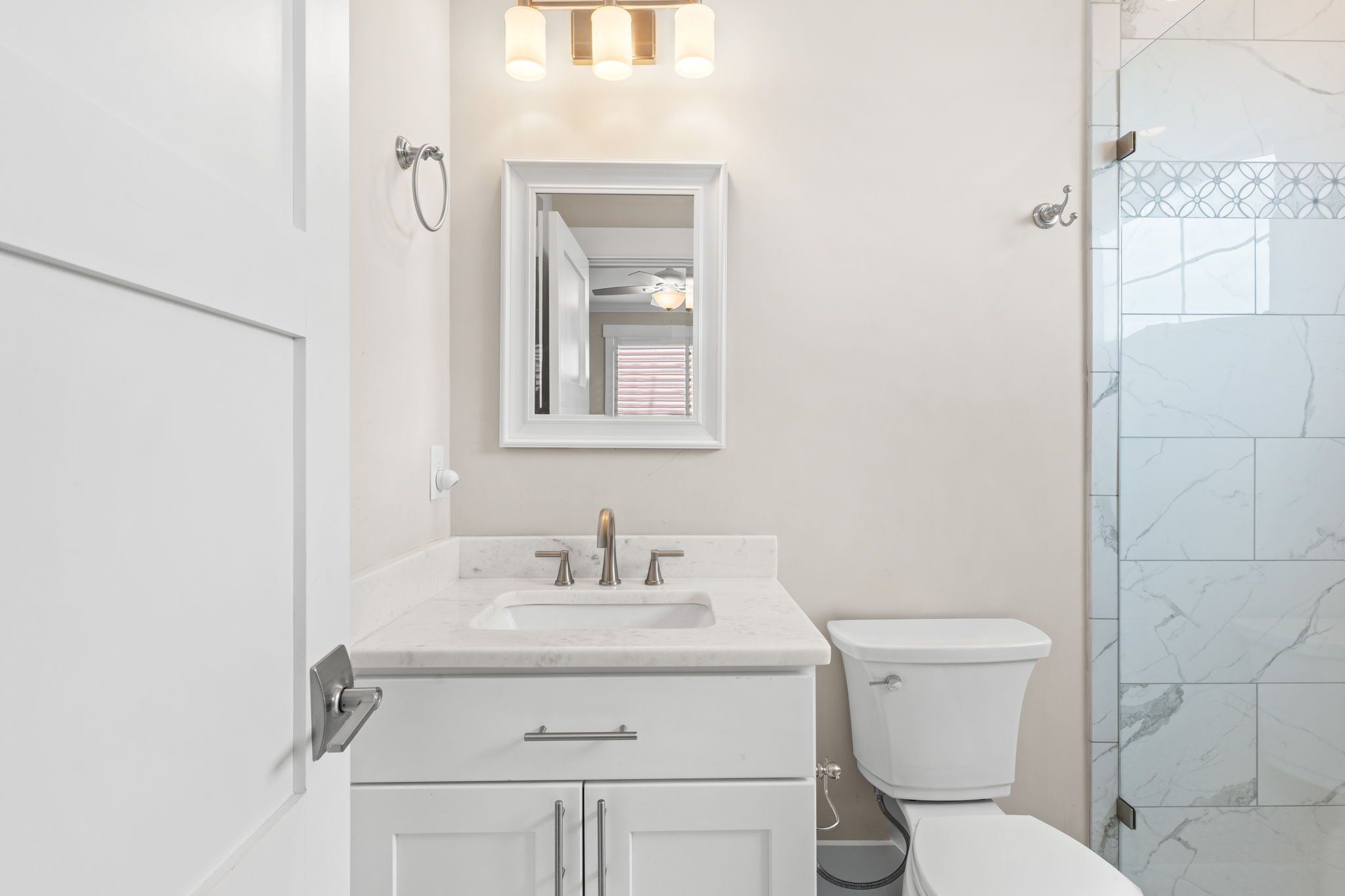 Une salle de bain moderne avec un lavabo blanc, un miroir et des toilettes.