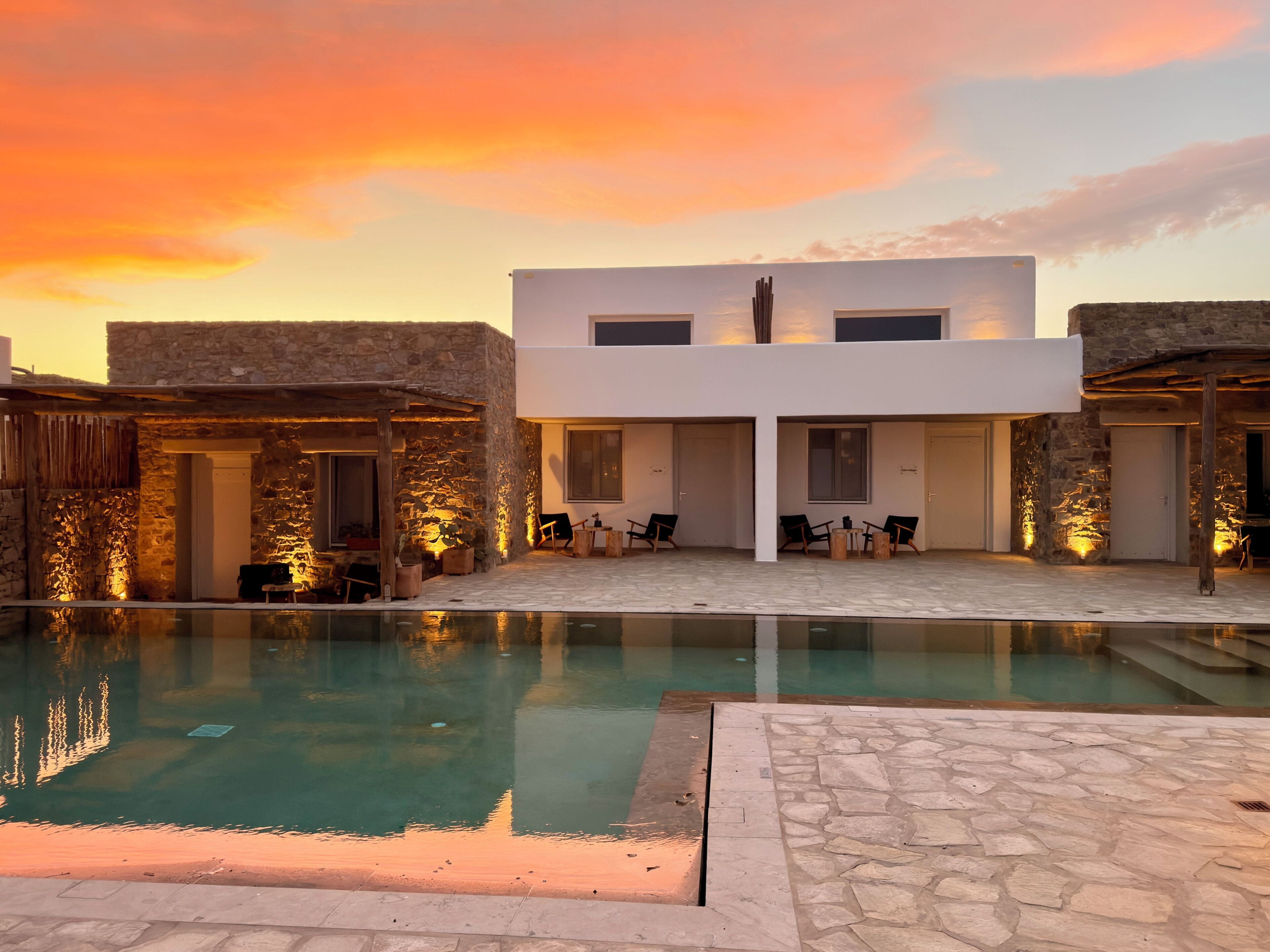 A modern building with a pool, stone walls, and outdoor seating.