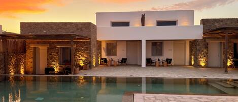A modern building with a pool, stone walls, and outdoor seating.