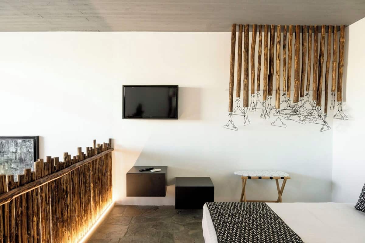 Ein modernes Schlafzimmer mit Fernseher, einer Wand aus Holzleisten, einem kleinen Bügelbrett und einem Bett.