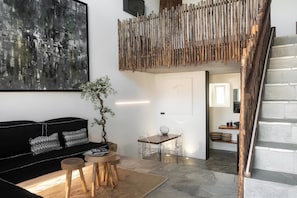 Ein modernes Wohnzimmer mit einem schwarzen Sofa, einem Holztisch und einem Essbereich mit transparenten Stühlen.