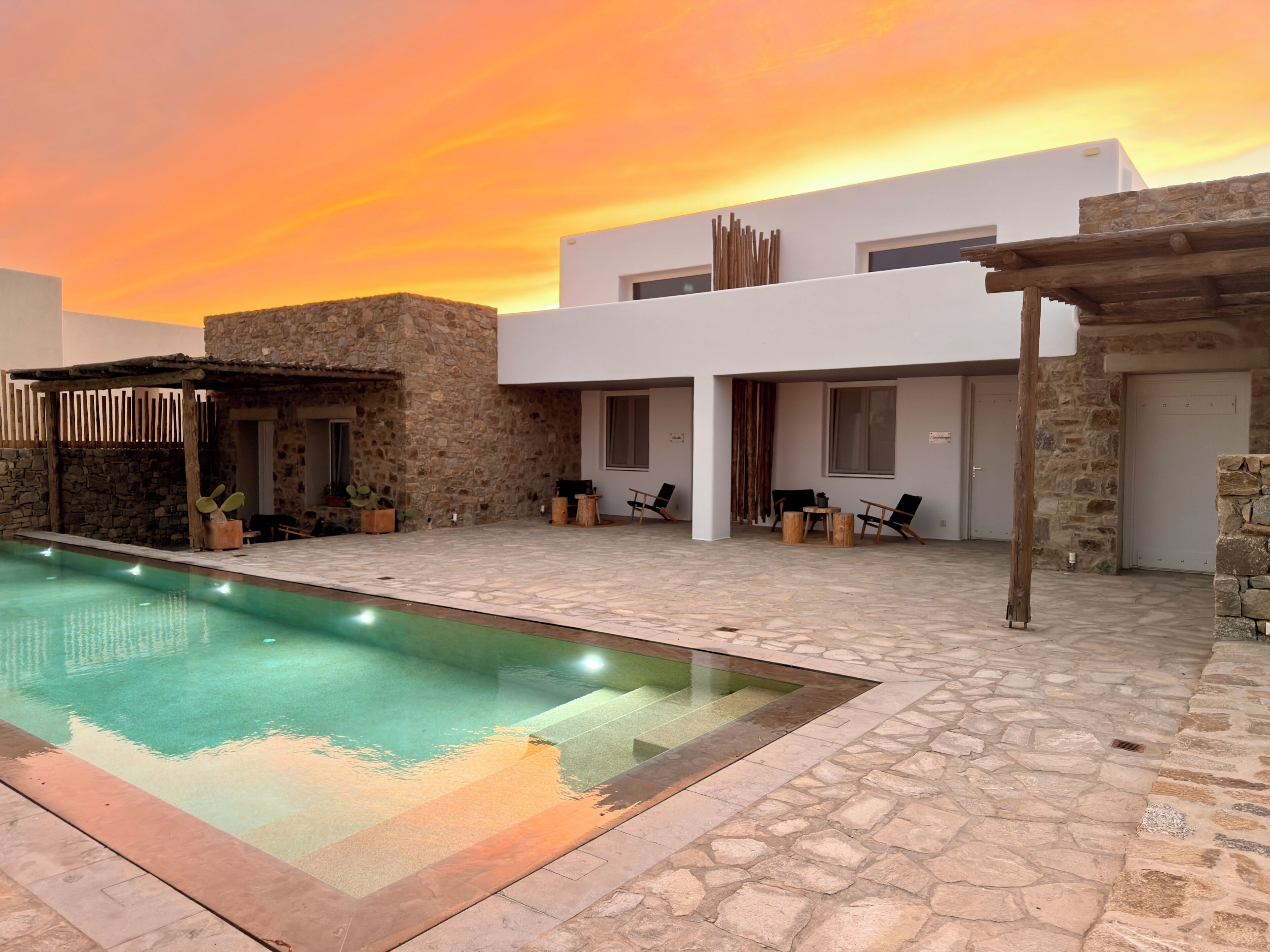 Um edifício moderno com piscina, paredes de pedra e área de estar ao ar livre.