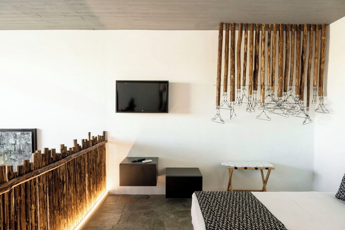 A modern bedroom with a TV, a wooden slat wall, a small ironing board, and a bed.