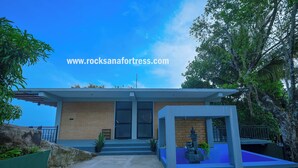 A modern building with a brick facade, large windows, and a blue outdoor seating area. - Rocksana Fortress Yoga & Retreat (Mawanella)