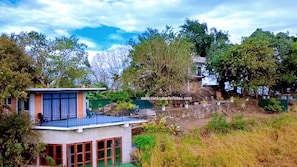 A modern house with a balcony, surrounded by trees and a rocky landscape. - Rocksana Fortress Yoga & Retreat (Mawanella)