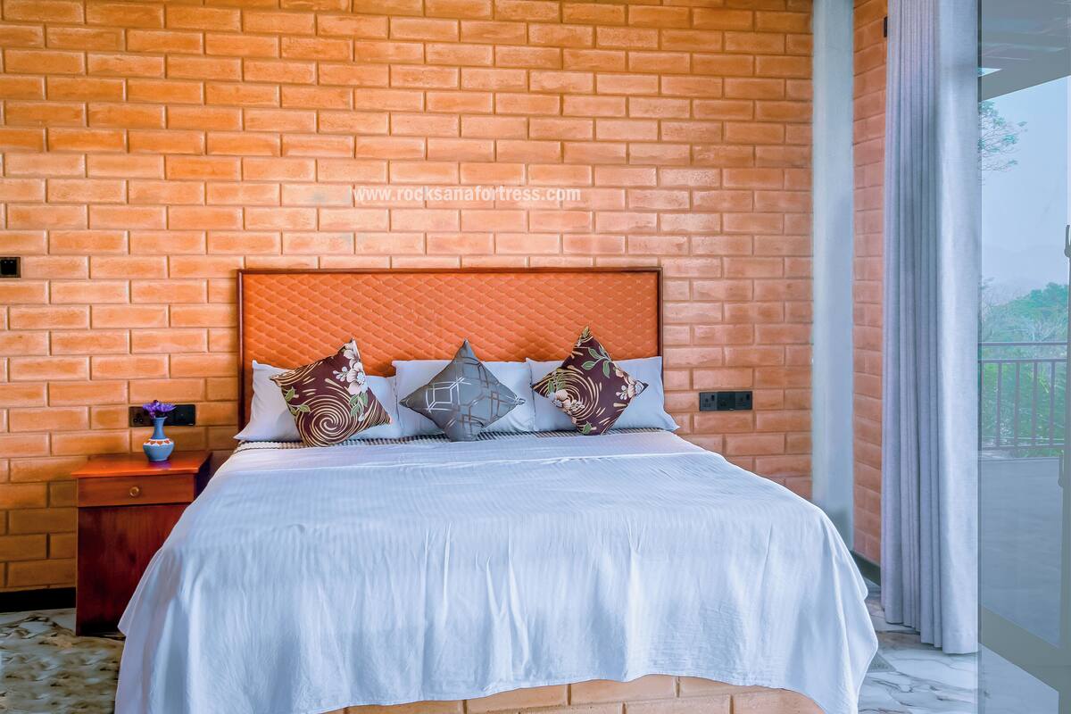 Ein Schlafzimmer mit Backsteinwand, einem Bett mit weißer Bettwäsche und dekorativen Kissen.