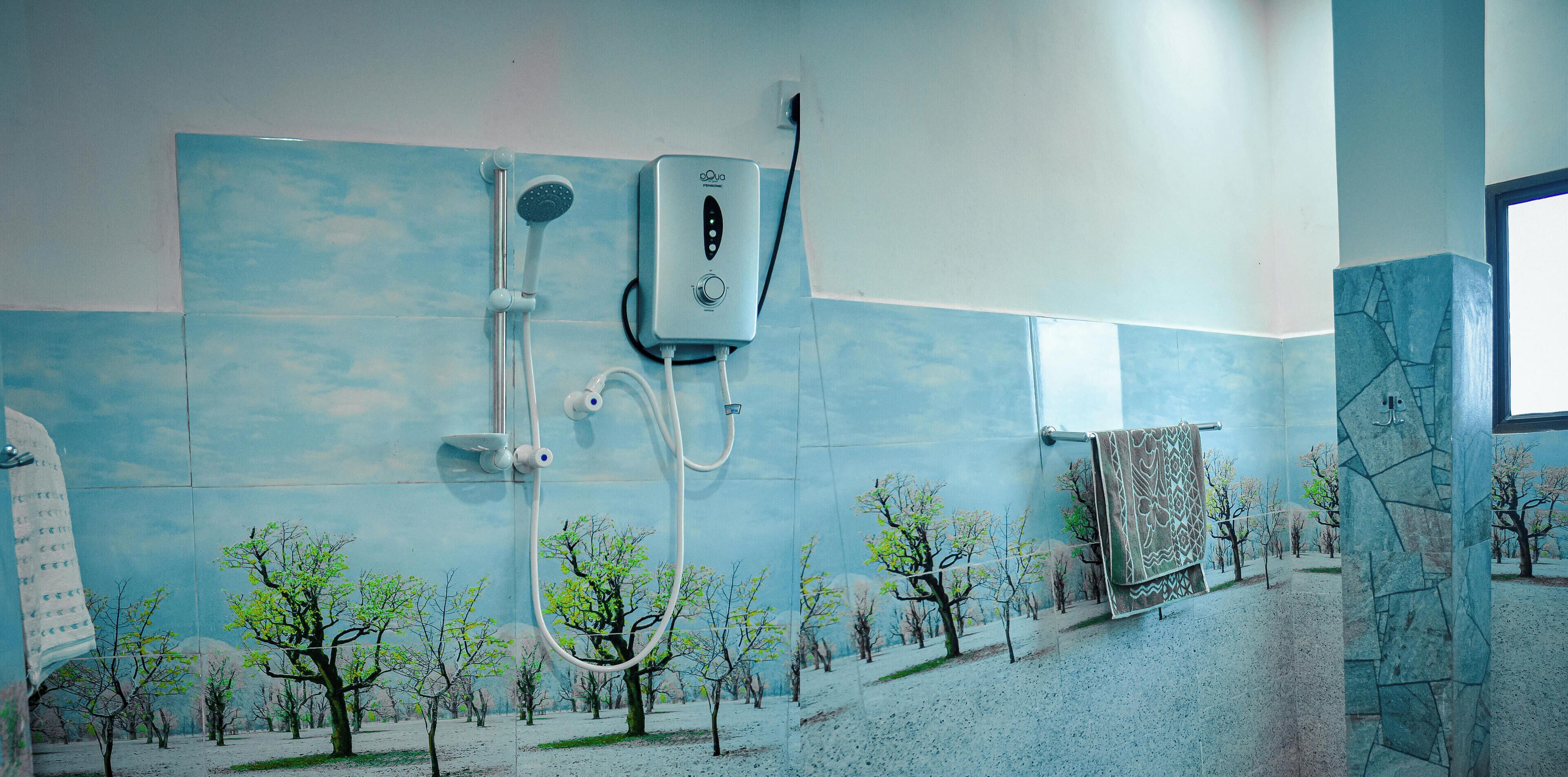 Un bagno con doccia, porta asciugamani e parete rivestita di piastrelle con un affresco raffigurante un albero.