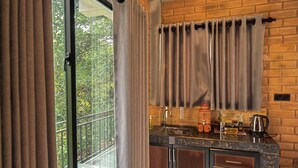 A modern kitchen with a marble countertop, wooden cabinets, and a brick wall. - Rocksana Fortress Yoga & Retreat (Mawanella)