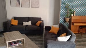 A living room with a dark grey sofa, a wooden coffee table, and a blue patterned wallpaper. - Nice house near Futuroscope (Neuville-de-Poitou)