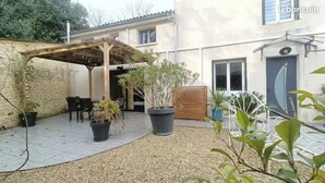 A patio area with a pergola, seating, and potted plants. - Nice house near Futuroscope (Neuville-de-Poitou)