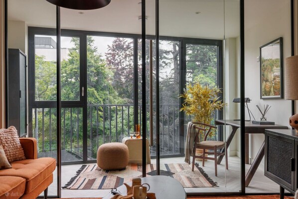 A modern living room with a large sliding glass door leading to a balcony, a sofa, a coffee table, and a TV. - The Ironworks (Dublin)