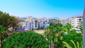 A coastal hotel with multiple floors, a central courtyard, and surrounding greenery. - Puerto Banus Apartment for 8 (Marbella)