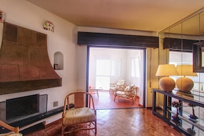 Un vaste espace de vie doté d’une cheminée, de sièges confortables et d’une table basse en verre.