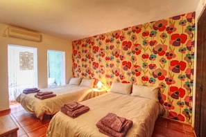 Une chambre d’hôtel avec deux lits, chacun agrémenté d’une serviette soigneusement pliée, d’une lampe de chevet et d’une fenêtre avec des rideaux.