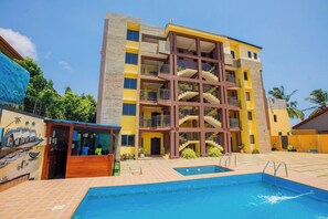 A multi-story hotel with a swimming pool, a covered area, and a mural on the side. - Stay Easy Apartment & Conference Centre (Accra)