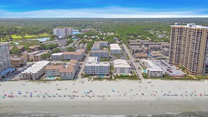 Een kustresort met hotels direct aan het strand, een zandstrand en golven.