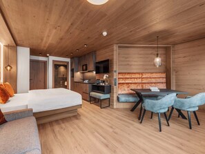 Een moderne slaapkamer met een groot bed, een bureau en een zithoek met stoelen.