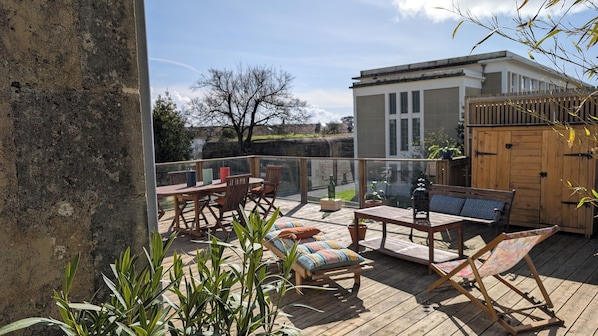 Eine Holzterrasse mit Gartenmöbeln, darunter ein Tisch und Stühle sowie eine Bank.