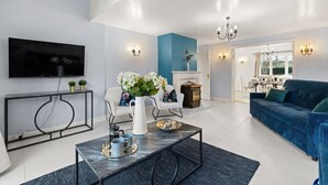 A modern living room with a flat-screen TV, a sofa, a coffee table, and a fireplace. - Tackley House - pet friendly near Oxford (Near Oxford)