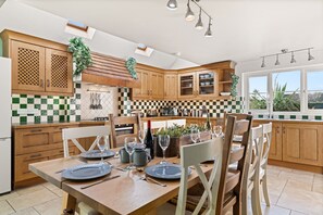 A modern kitchen with wooden cabinets, a dining table set for four, and a large window providing natural light.
