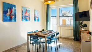 Ein Essbereich mit einem Tisch für vier Personen, blauen Stühlen und einem Fenster mit Vorhängen.