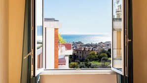 Blick aus einem Fenster auf eine Küstenstadt mit Gebäuden und blauem Himmel.
