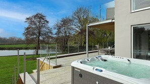 A hot tub on a deck with a view of a lake and trees.