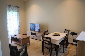 Un coin repas équipé d’un téléviseur, de meubles en bois et d’une table dressée pour deux personnes.