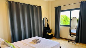 Un dormitorio con cama, espejo, una mesita y una ventana con cortinas.