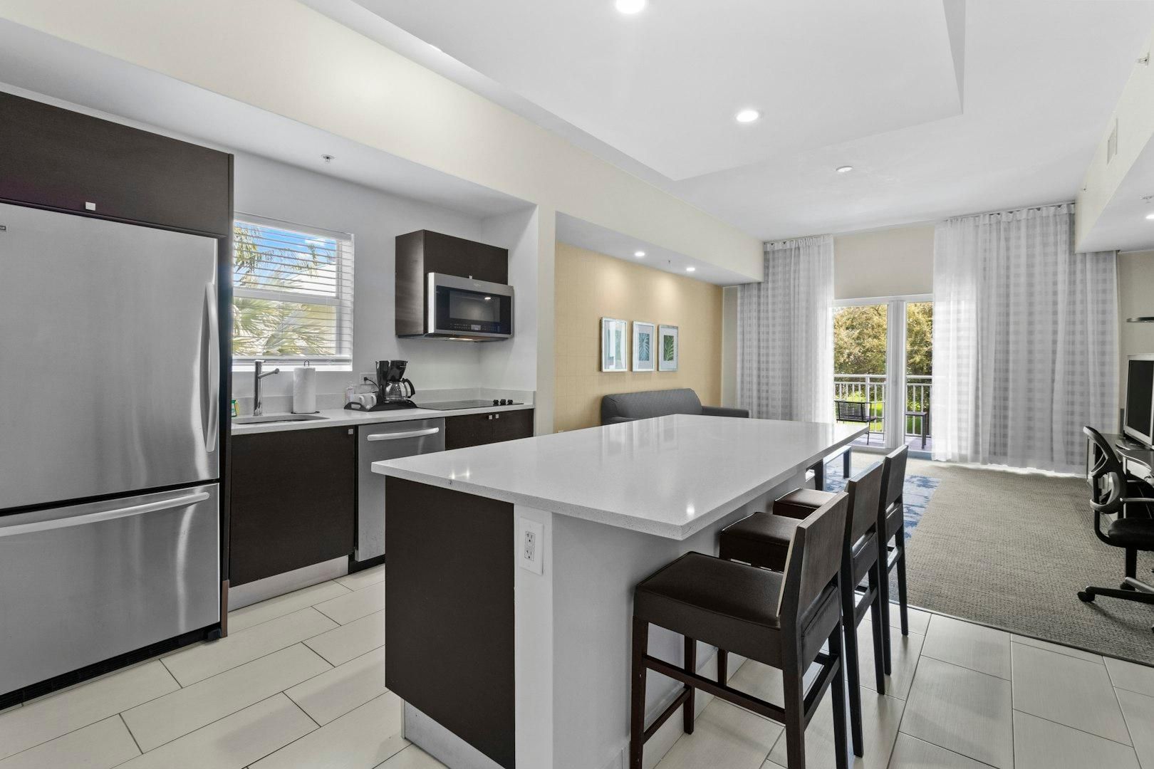 A modern kitchen with a central island, stainless steel appliances, and a dining area with a TV.