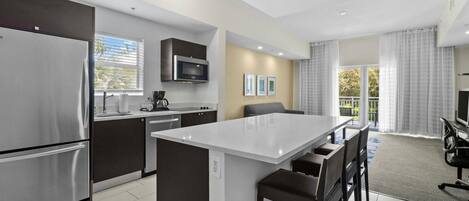 A modern kitchen with a central island, stainless steel appliances, and a dining area with a TV.