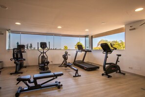 A modern gym with various exercise equipment, large windows, and a wooden floor. - Elegant Lagoon Retreat for 4 (Casares)