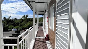A covered outdoor corridor with a wooden deck, white railings, and a view of the surrounding greenery. - Overseas Ryukyu studies Homestay (Liuqiu)